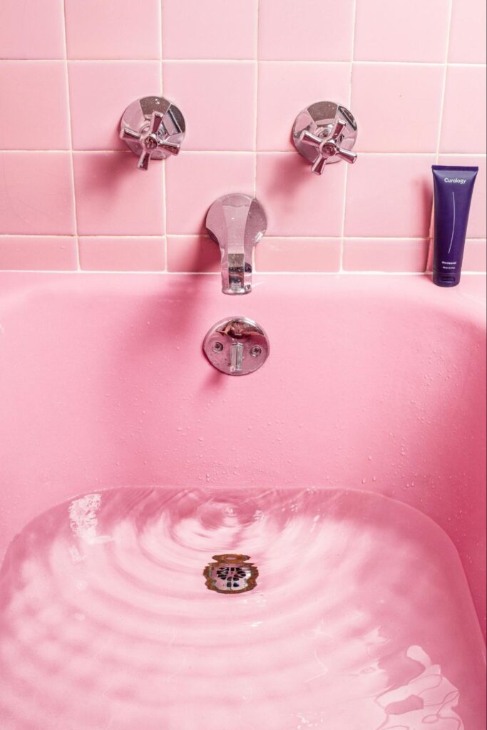 Pink bathroom with pink bathtub filled with water