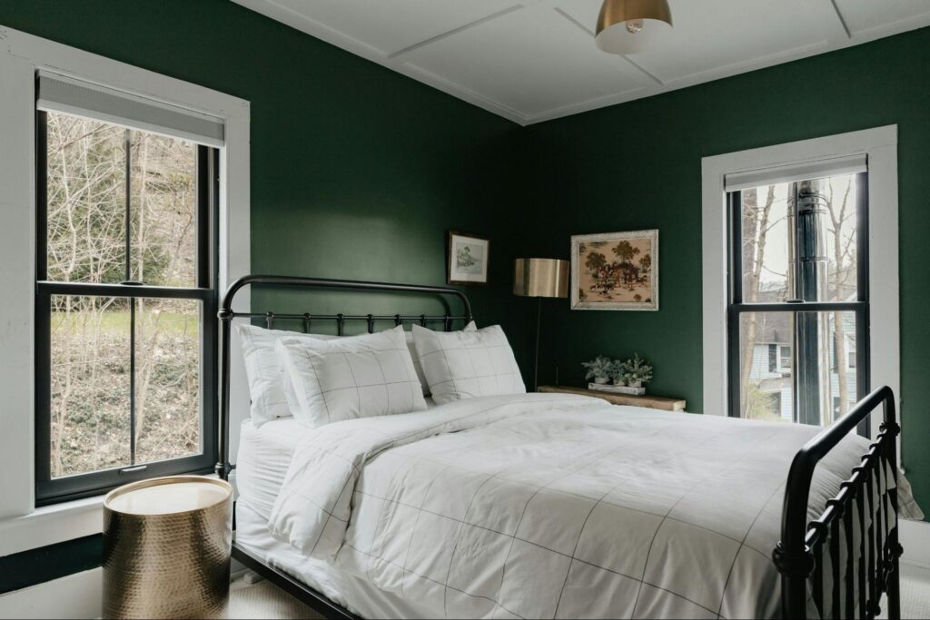 Small bedroom with green walls and white and black accents