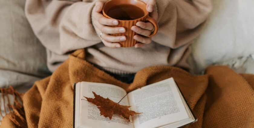A woman reading a book and drinking tea