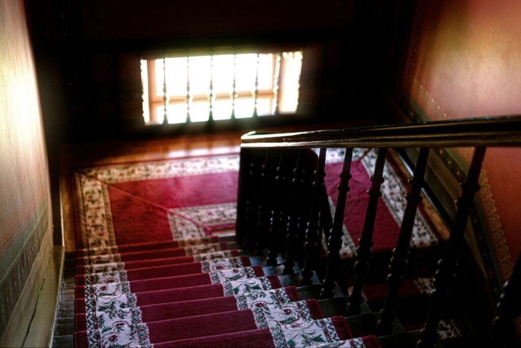 A wooden staircase with red rug on it