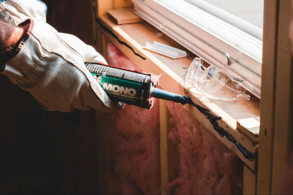 Person gluing plasterboard over insulation material