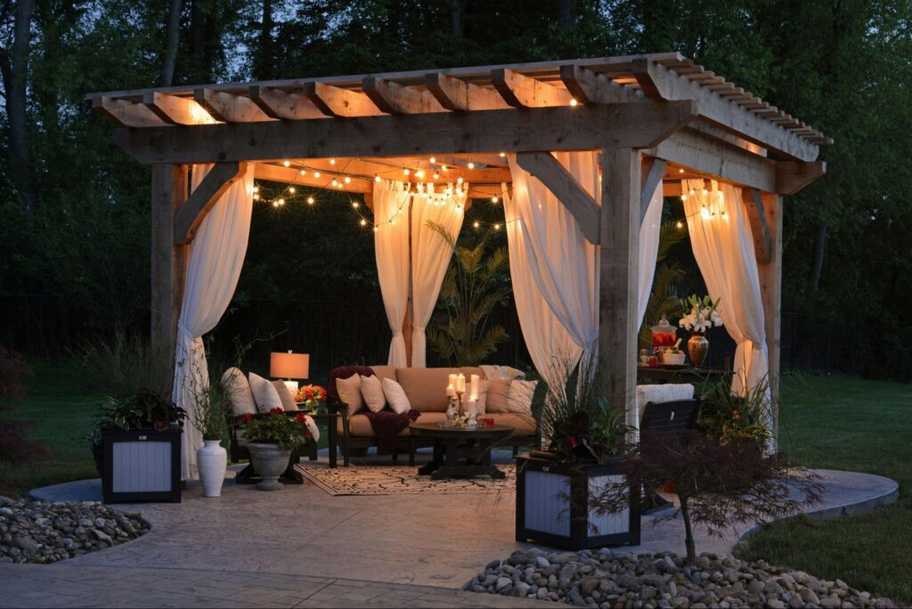 Beautiful patio design with a pergola, flowwing curtains, comfy furniture and lights