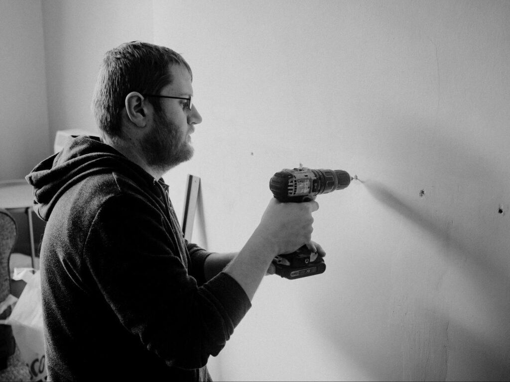 Balck and white image of a person drilling in drywall